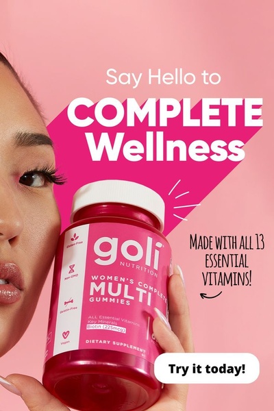 A close-up, high-energy product shot featuring a woman holding a bottle of Goli Women's Complete Multi Gummies against a vibrant pink backdrop.